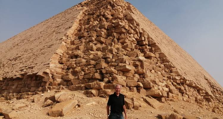 Een persoon die voor een piramide staat.