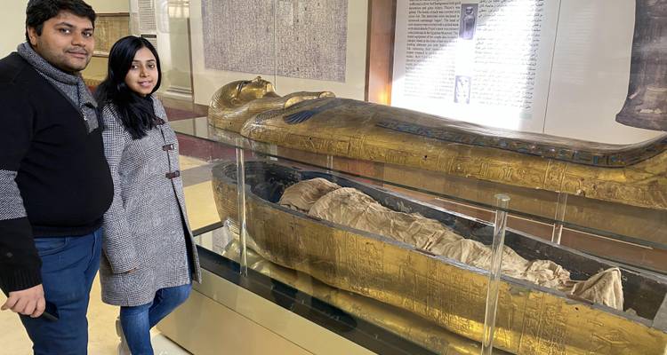 Twee mensen die naast een oude Egyptische sarcofaag staan.