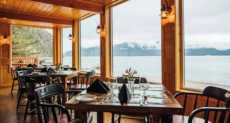 Essbereich mit großen Fenstern, die einen malerischen Blick auf einen See bieten.