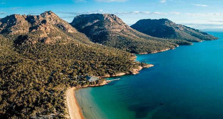 Aerial view of a coastal area with mountains and blue sea.