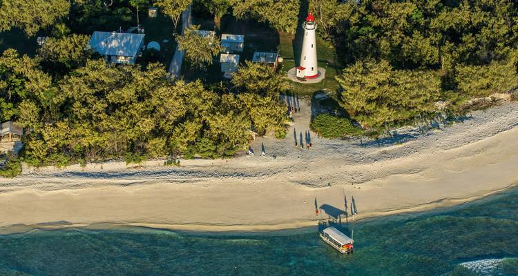 Luftaufnahme eines Strandes mit einem Leuchtturm und Gebäuden.