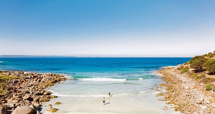 Plage avec un rivage rocheux et des eaux bleues claires.