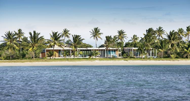 Propriété en bord de mer entourée de palmiers avec vue sur l'océan.