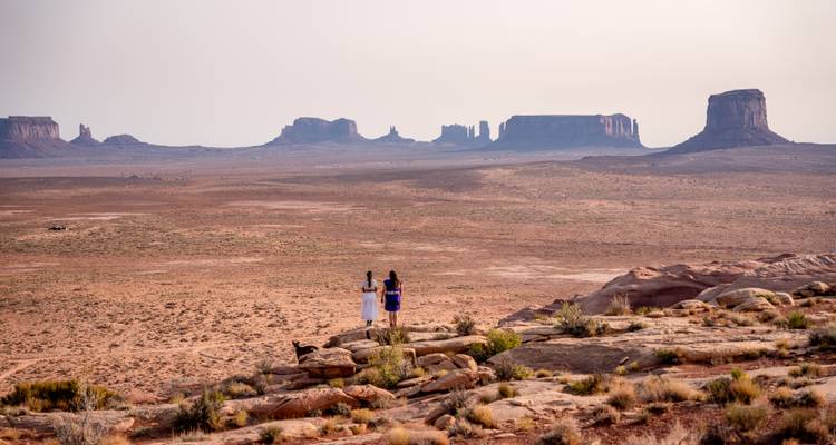Two people and a dog looking out over a desert landscape.