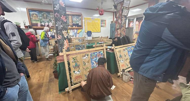 Los visitantes observan a los artistas pintando thangkas bhutaneses tradicionales dentro de un taller de escuela de arte.