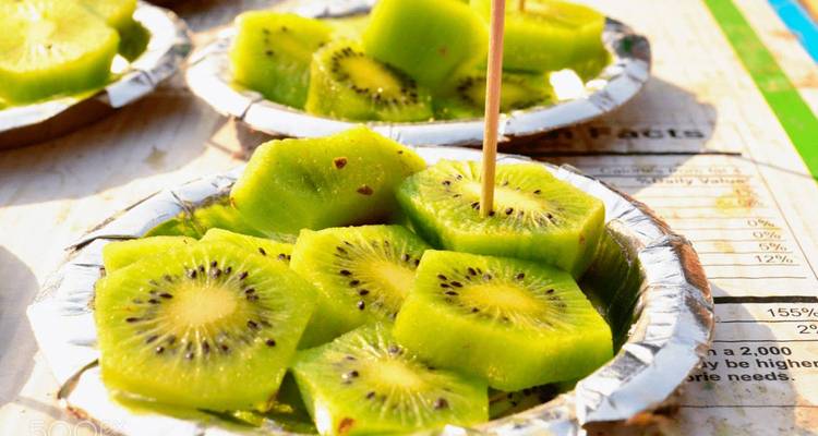 Plakjes verse kiwi geserveerd in een kleine bak met een tandenstoker.