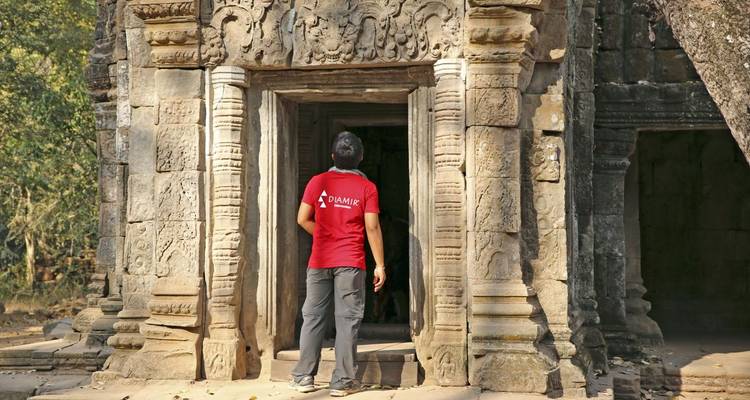Person, die am Eingang eines steinernen Tempels steht.