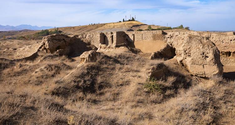 Ruinas secas y azotadas por el viento y montículos de tierra bajo un cielo azul