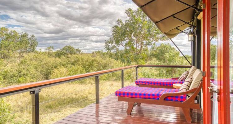 Ein Holzdeck mit Liegestühlen mit Blick auf eine natürliche Landschaft.