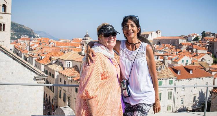 Two smiling travellers pose above Dubrovnik’s red-tiled rooftops and Adriatic coastline.