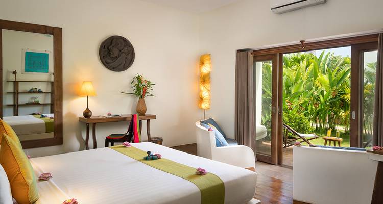 Bright, tropical resort room with garden view, stylish decor and double bed.