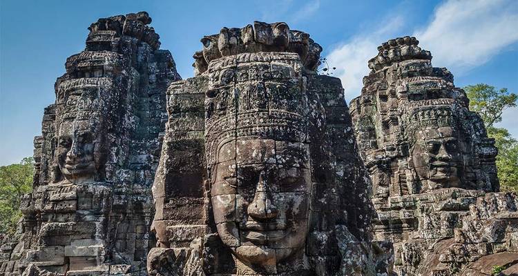 Stone faces of Bayon temple towering against a clear sky in Angkor Thom.