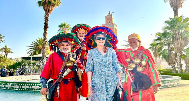 Les vendeurs d'eau traditionnels vêtus de rouge vif posent avec un touriste devant la mosquée Koutoubia à Marrakech.