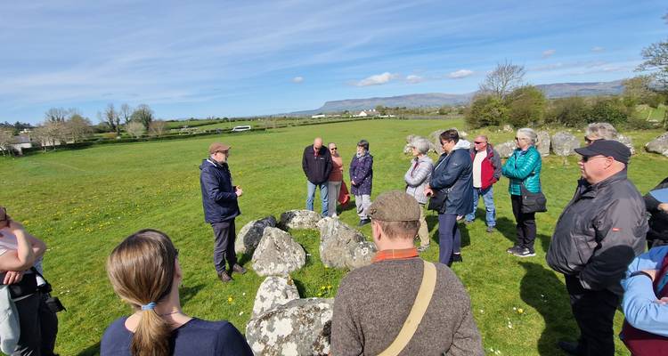 Groupe de touristes écoutant un guide dans une zone herbeuse.