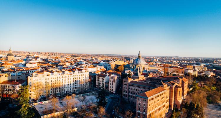 Panorama aéreo de los tejados y monumentos de Madrid brillando en la luz del atardecer.