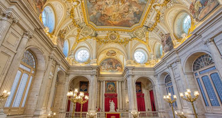 Salón barroco suntuoso con techos dorados ornamentados y candelabros dentro del Palacio Real de Madrid.