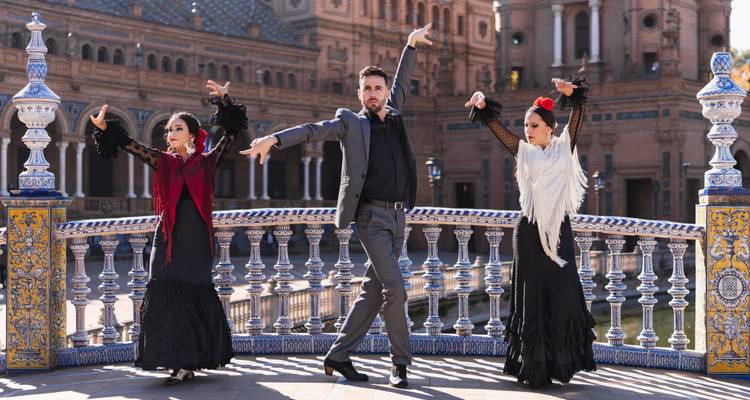 Tres bailarines de flamenco adoptan poses dramáticas en el puente de azulejos de la Plaza de España de Sevilla.