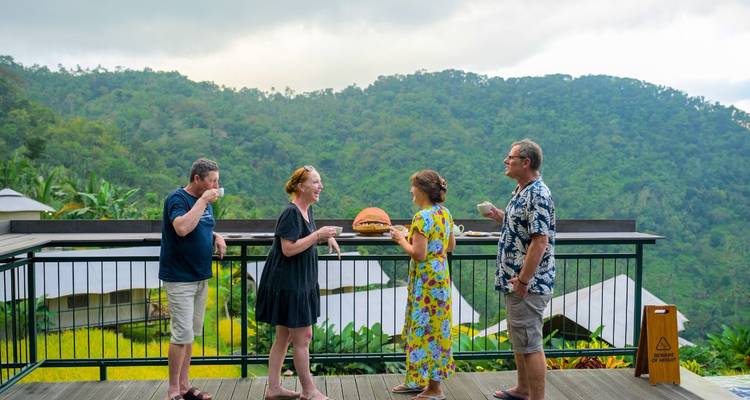 People enjoying a scenic view from a deck with surrounding hills.