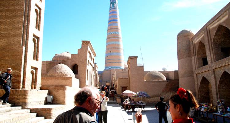 Touristen erkunden eine historische Stadt mit einem hohen dekorativen Turm.