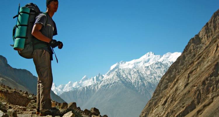 Hiker with a heavy backpack on a rugged mountain trail.