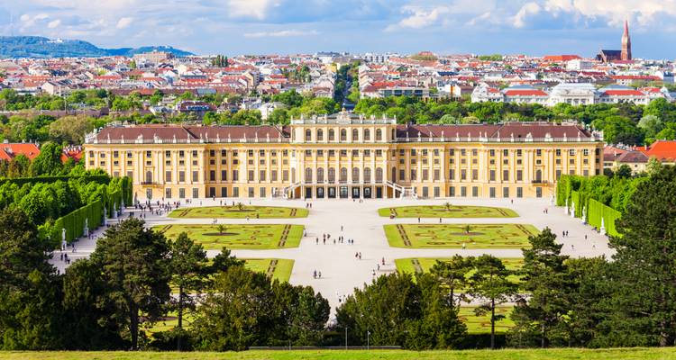 Schönbrunn Palace with formal gardens and a cityscape in the background.