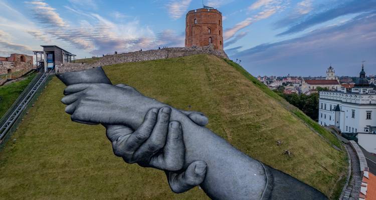 Riesiges Wandgemälde von Händen an einem Hang mit einem Wachturm im Hintergrund.