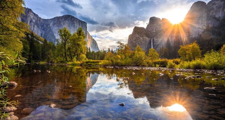 Schilderachtig uitzicht op Yosemite National Park met een rivier die bergen weerkaatst en een ondergaande zon.