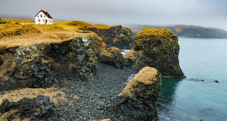 Coastal cliffs with ocean and isolated house.