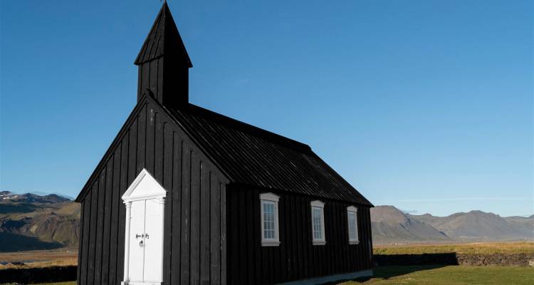 Black church with mountains in the background.