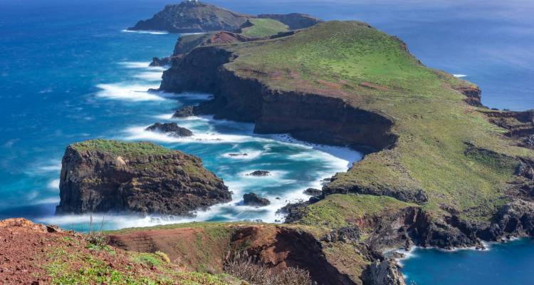 Dramatic coastline with cliffs, green hills, and ocean waves.
