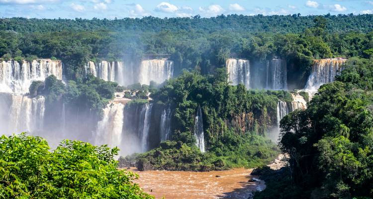 Wijd uitzicht op de Iguazu-watervallen met heldere lucht en weelderige bomen.