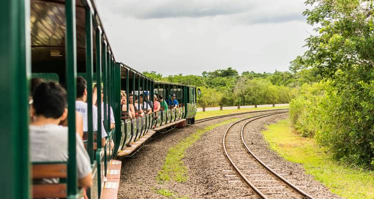Openluchttrein met passagiers die door een natuurlijk landschap reist.