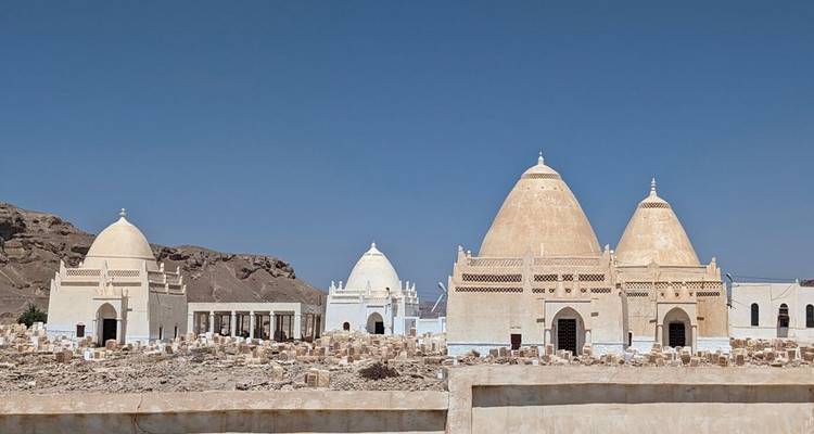 Fila de mausoleos abovedados de color crema que se alzan aislados en un cementerio desértico y rocoso.