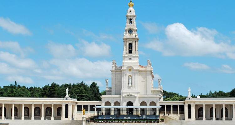 Une grande basilique blanche avec des colonnades sous un ciel bleu.