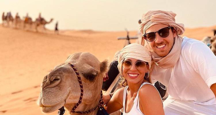 Smiling couple on a camel in the desert.