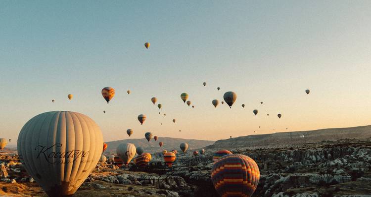 Hot air balloons at sunrise over a rocky landscape.