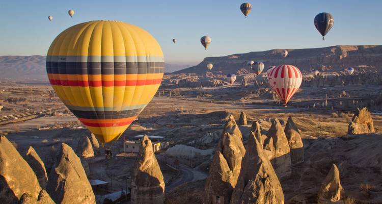Colorful hot-air balloons drift above Cappadocia’s surreal fairy-chimney landscape at sunrise.