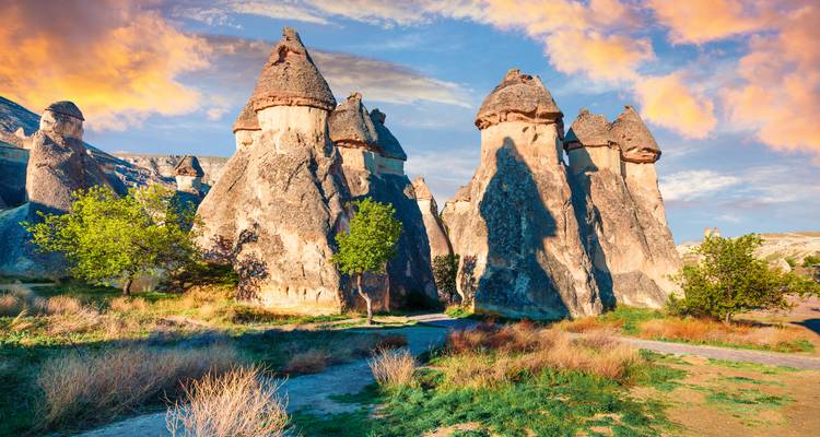 Mushroom-shaped rock pinnacles of Pasabag glow under a vibrant sunset sky in Cappadocia.
