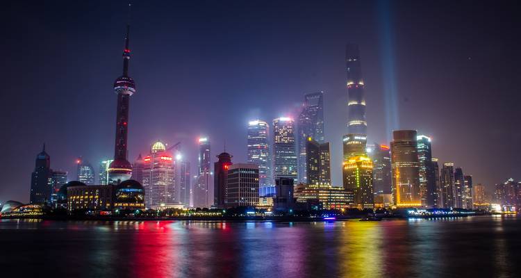Shanghai skyline verlicht in de nacht met kleurrijke lichten.