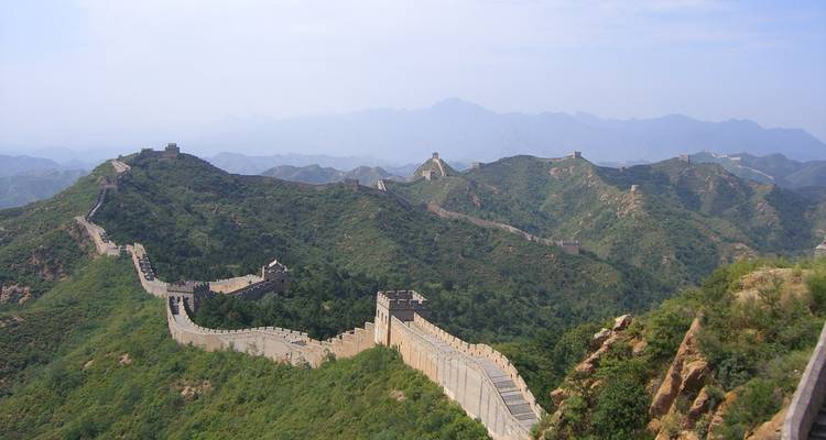Grote Muur van China slingerend door het groen onder een heldere hemel.