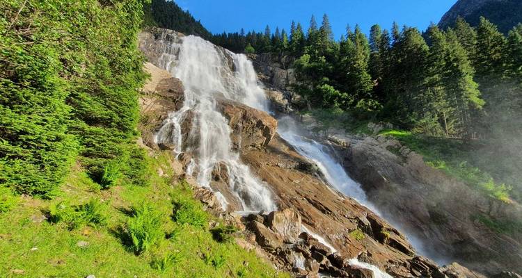 Une majestueuse cascade dégringolant le long de falaises rocheuses entourées d'une forêt verdoyante.