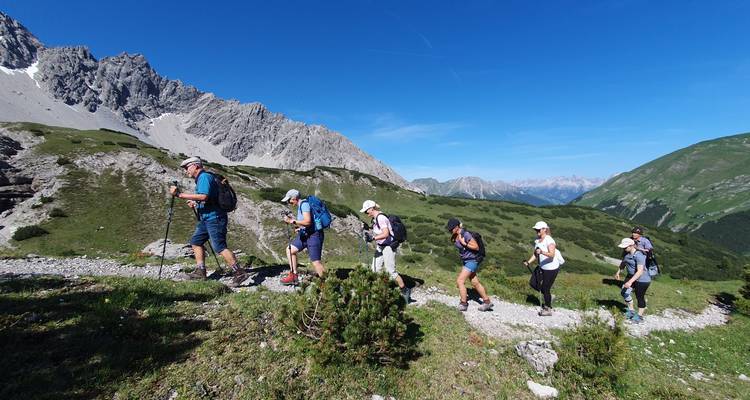 Un groupe de randonneurs marchant le long d'un sentier de montagne sous un ciel bleu clair.