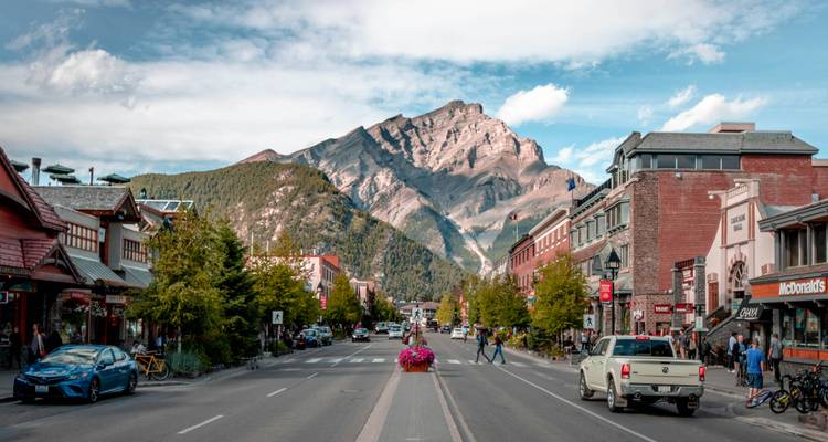 A bustling town street with mountain views in the background.