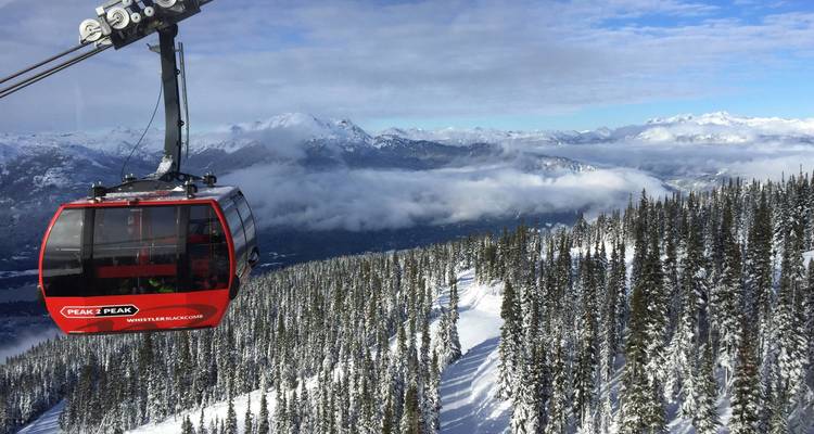 Red cable car over a snowy mountain landscape.