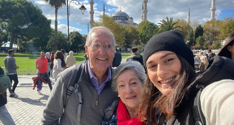Drie mensen die een selfie maken met een historische moskee op de achtergrond.