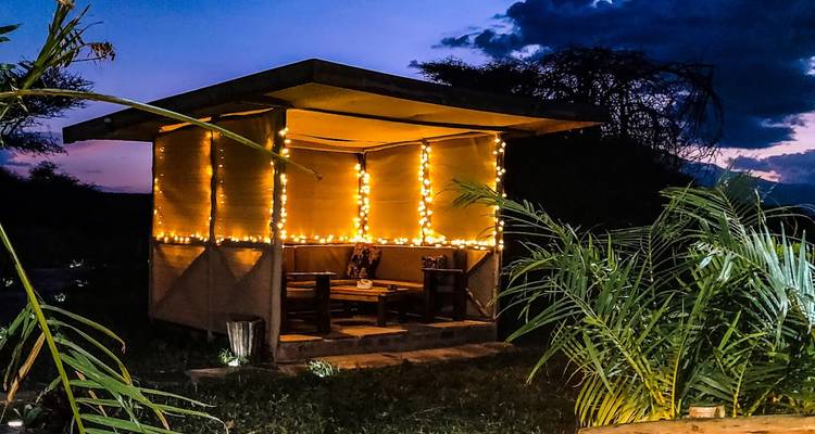 Ein gemütlicher Außensitzbereich, der in der Dämmerung von Lichterketten beleuchtet wird.