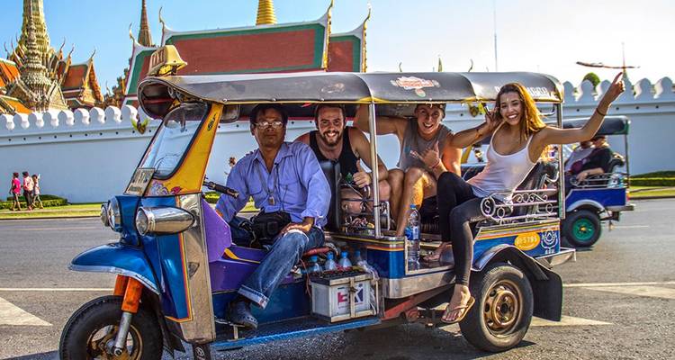 Group of people enjoying a tuk-tuk ride in the city.