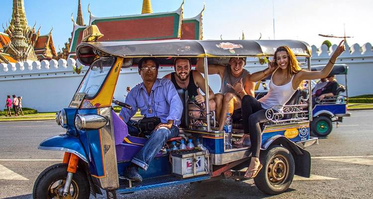 Glimlachende reizigers genieten van een leuke tuk-tuk rit langs de tempelwallen van Bangkok.