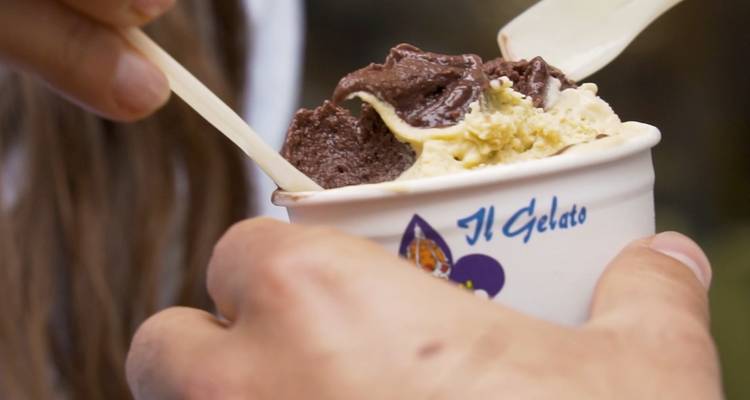 Primer plano de las manos de una persona sosteniendo una copa de helado con una cuchara.