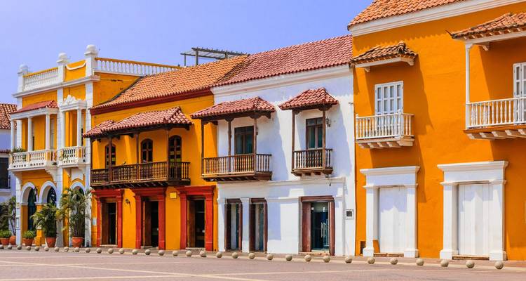Rangée de bâtiments coloniaux peints de couleurs vives avec des balcons bordant une place ensoleillée dans la vieille ville de Carthagène.